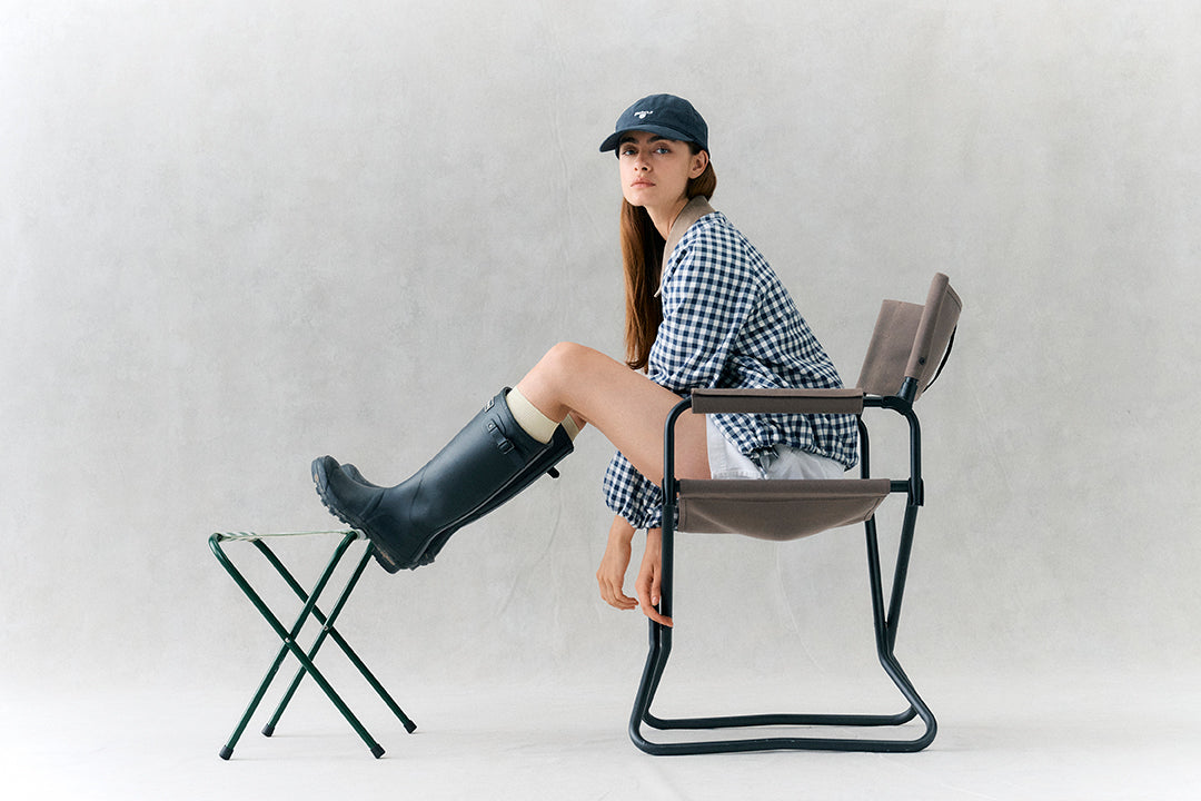 Person sitting on a modern chair with one leg on a small stool against a plain background
