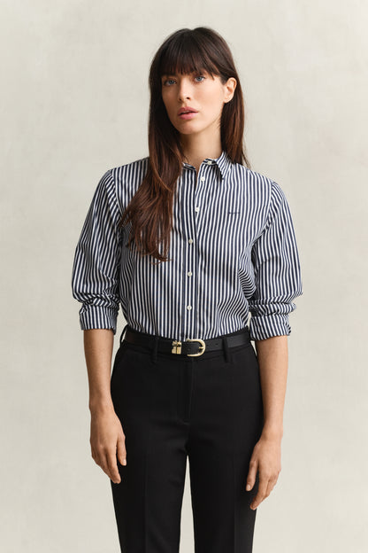 Woman wearing a striped shirt and black pants against a plain background