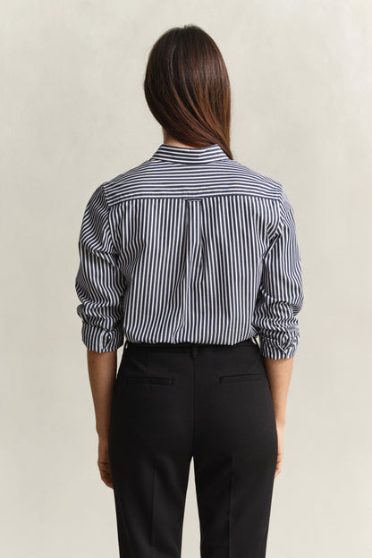 Person wearing a black and white striped shirt with rolled-up sleeves and black pants on a beige background