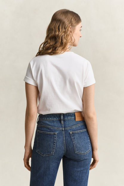 Person wearing a white t-shirt and blue jeans on a beige background