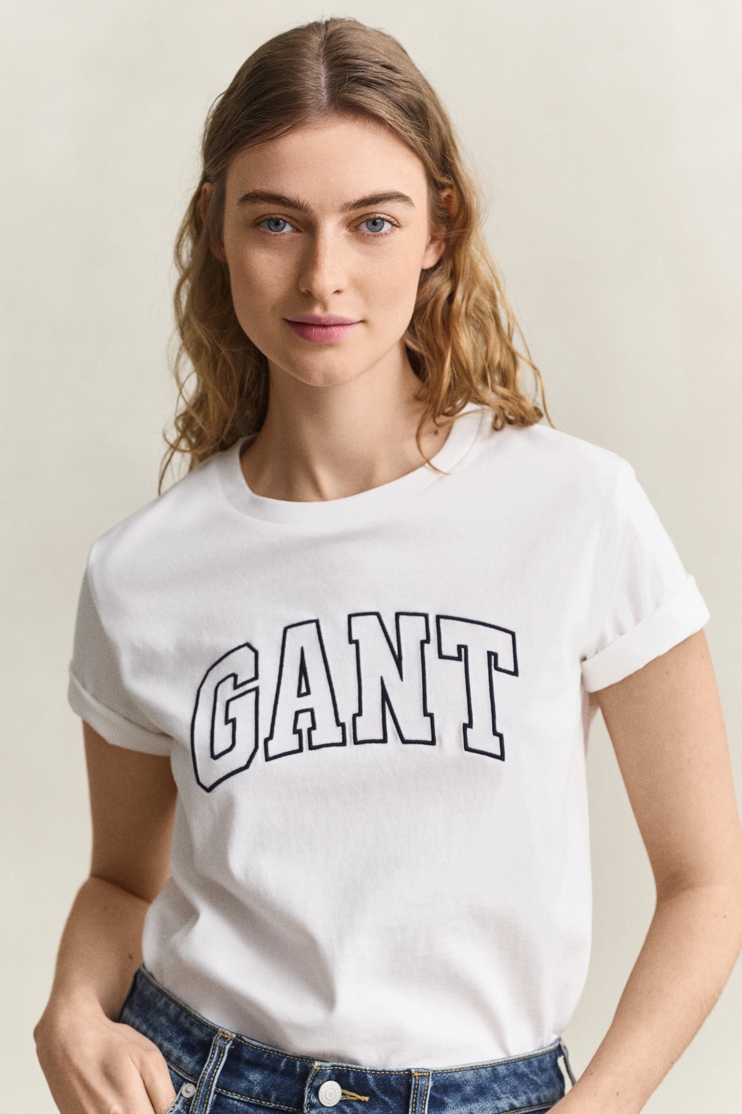 Woman wearing a white t-shirt with 'GANT' logo against a plain background
