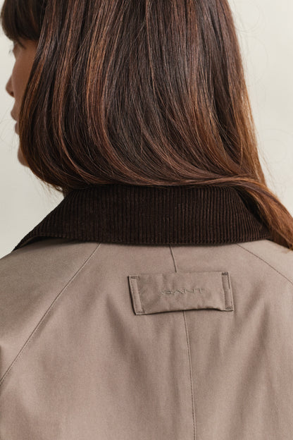 Close-up of a person wearing a brown jacket with a visible brand logo.