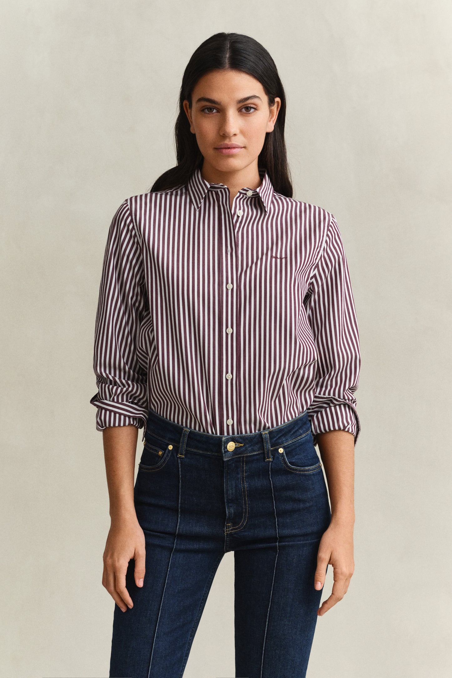 Woman wearing a striped shirt and jeans against a plain background