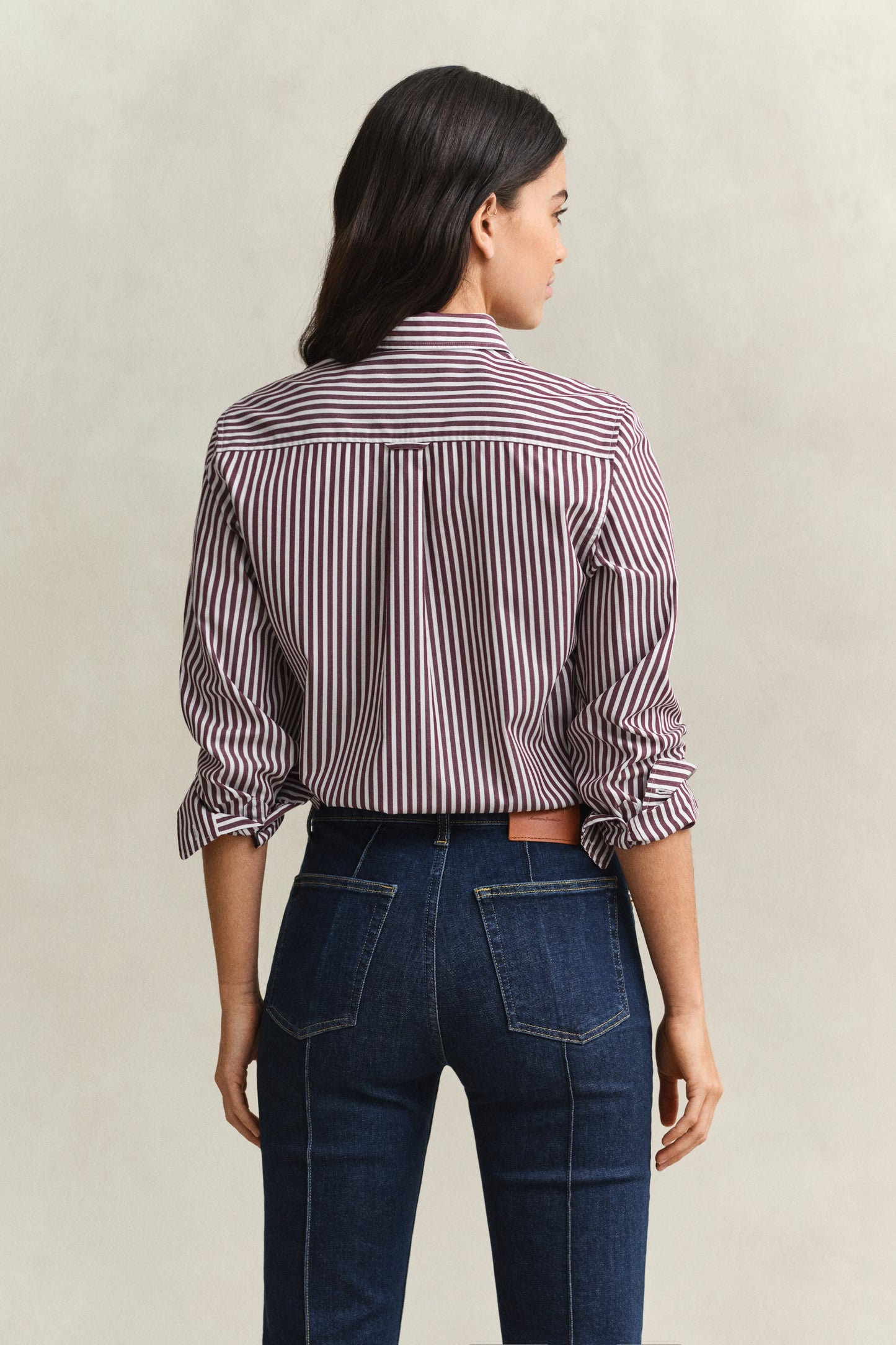 Woman wearing a striped shirt and jeans on a plain background