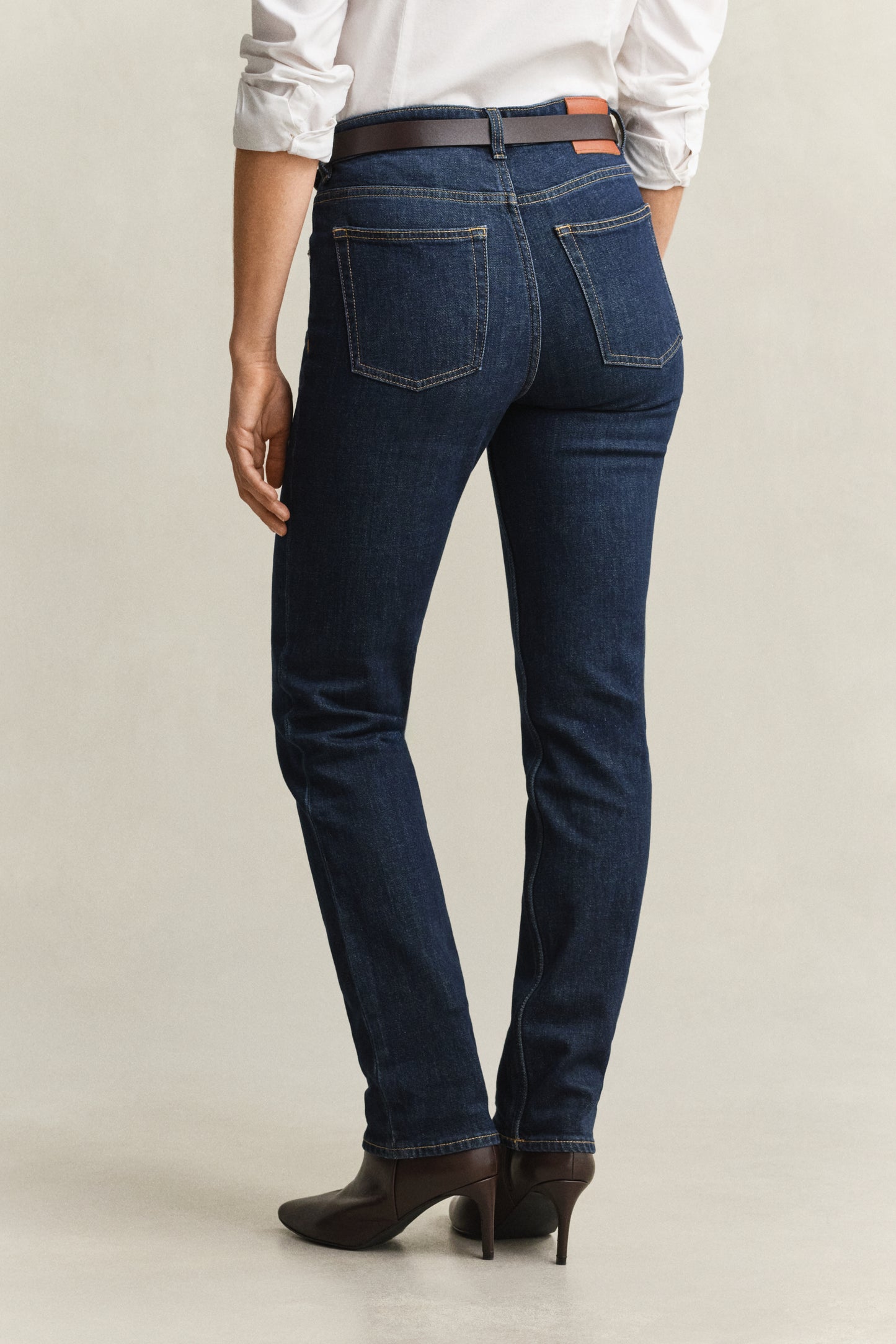 Person wearing dark blue jeans on a plain background