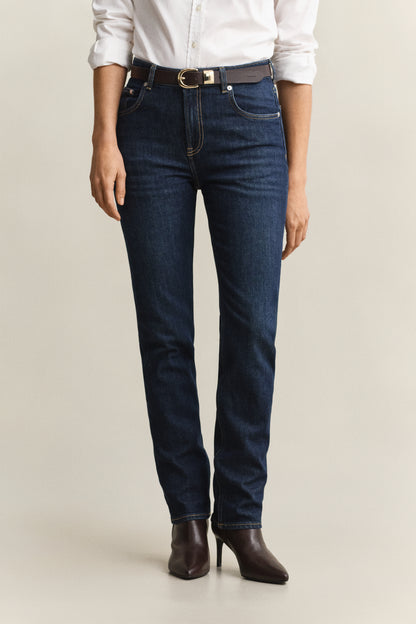 Person wearing dark blue jeans and a white shirt on a beige background