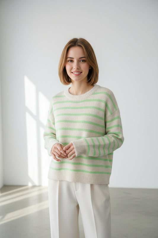 Striped sweater with green and beige pattern on a hanger against a white background