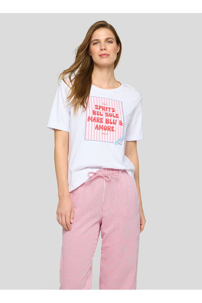 Woman wearing a white t-shirt with red text and pink checkered pants on a gray background