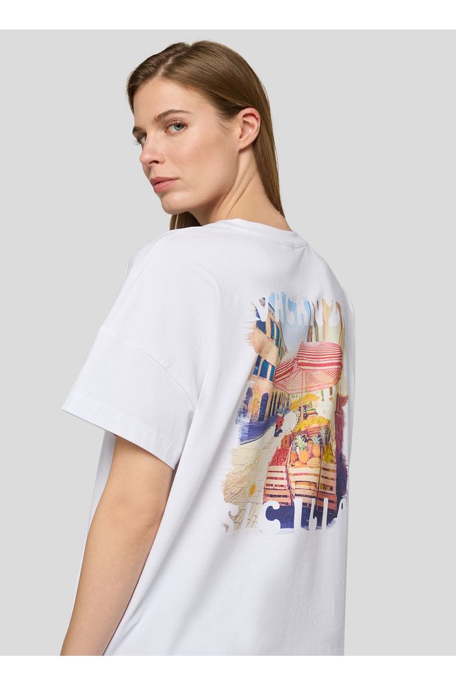 Woman wearing a white t-shirt with a colorful graphic design on a light gray background