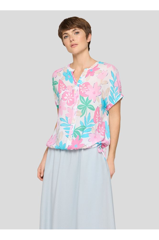 Woman wearing a colorful floral blouse with a light gray skirt on a white background