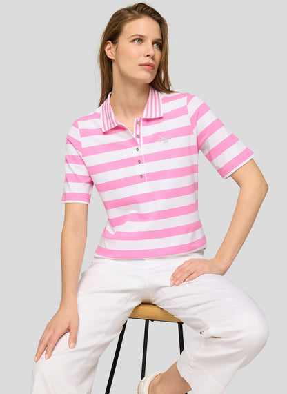 Woman wearing a pink and white striped polo shirt and white pants on a gray background