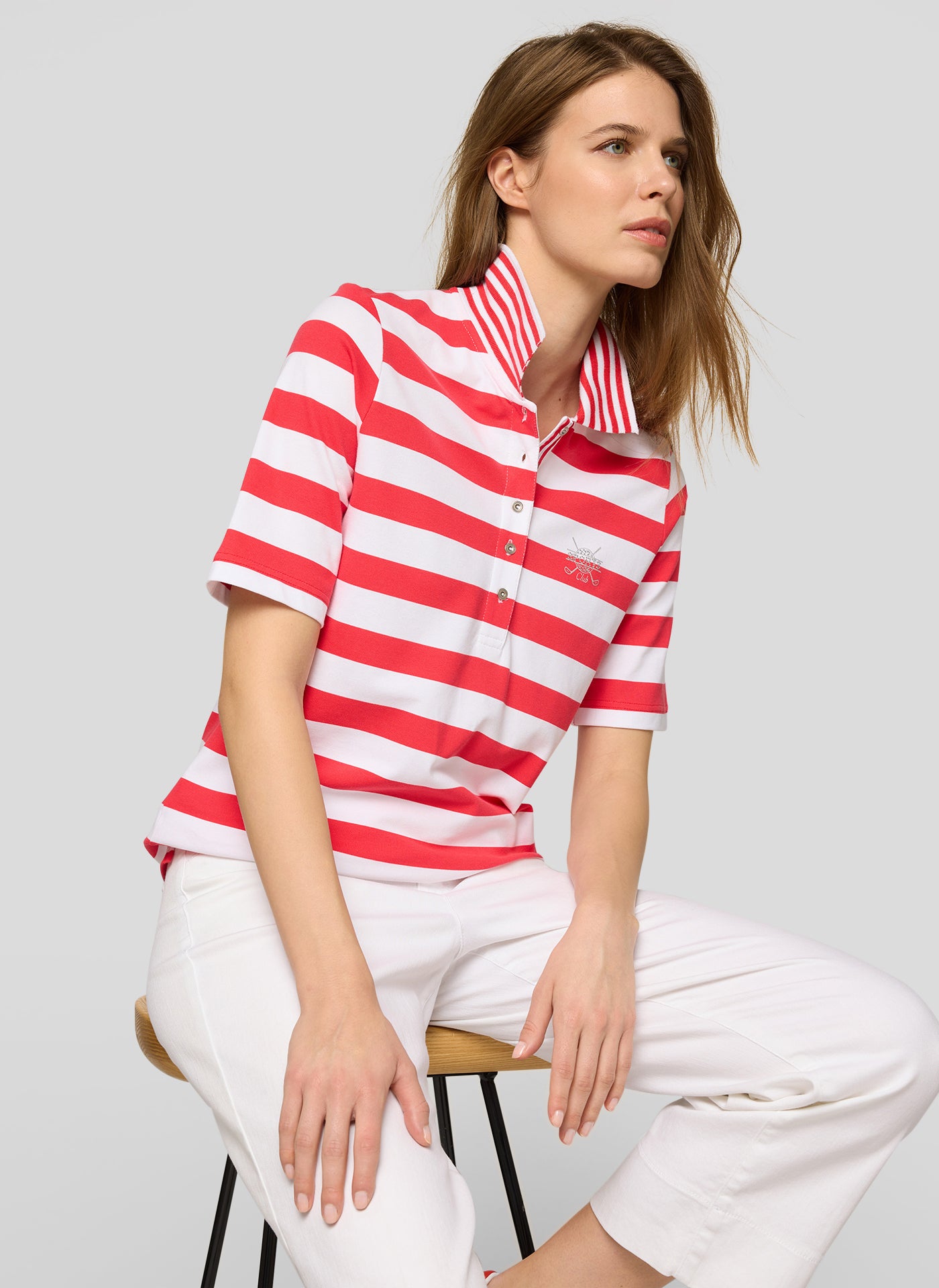 Woman wearing a red and white striped shirt and white pants on a gray background