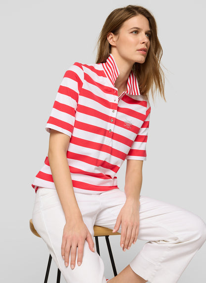 Woman wearing a red and white striped shirt and white pants on a gray background