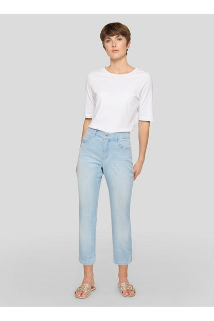 Woman wearing a white top and light blue jeans on a gray background