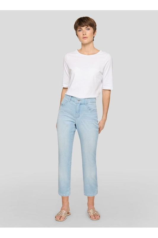 Woman wearing a white top and light blue jeans on a gray background