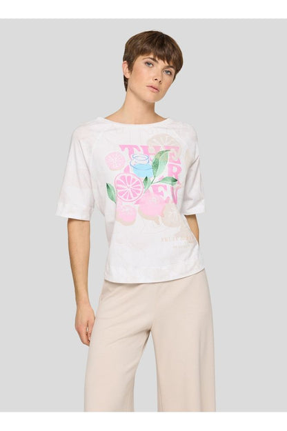 Woman wearing a white t-shirt with colorful floral design on a plain background