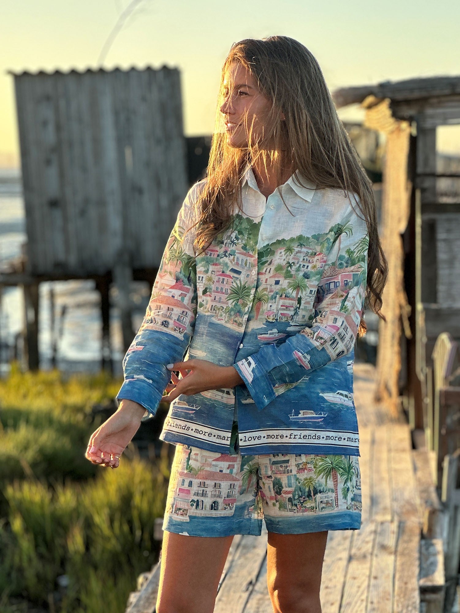 Woman wearing a colorful outfit with a scenic design, standing on a wooden path.