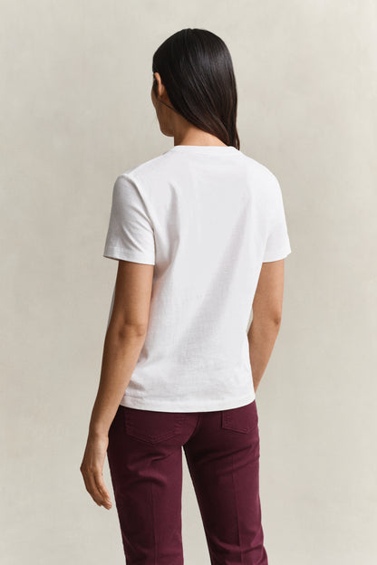 A woman shown from the back wearing a plain white short-sleeve crewneck t-shirt and dark burgundy pants, standing against a neutral light beige background.